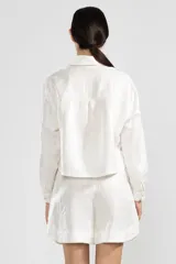 Camisa blanca de lino italiano con hilo metalizado, cuello clásico y botón de flor en el cuello.