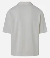 Camisa de jacquard color crema, de corte oversized, con cuello solapa, manga corta, abotonadura frontal, bolsillo en el pecho y textura en relieve.