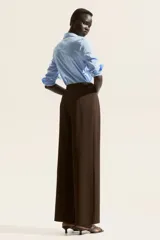 Pantalón sastre marrón de corte ancho, con pinzas y cinturón decorativo con hebilla metálica.