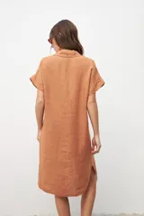 Vestido camisero color tostado de lino con cuello clásico, manga corta con dobladillo, cierre frontal con botones y bolsillo de parche en el pecho.