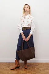 Camisa azul marino con estampado floral en color lila, cuello mao con volantes, cierre frontal de botones y mangas largas abullonadas con puños elásticos.