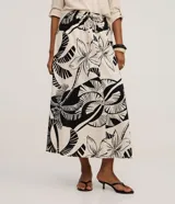 Pollera larga (midi) de corte evasé, con cintura elástica y lazo. Presenta un estampado grande en blanco y negro de motivos tropicales como hojas de palmera y flores.