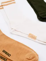 Pack de tres pares de medias deportivas de caña corta, con diseño a rayas en el borde superior y logo de la marca en el tobillo. Incluye un par negro con rayas blancas, un par blanco con rayas negras y un par gris con rayas blancas.