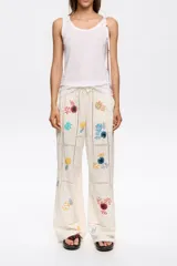 Pantalón de corte recto color crema con bordados florales multicolores.