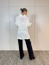 Polerón largo blanco de acrílico con cuello alto y diseño trenzado.