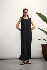 Vestido largo negro sin mangas, con cuello redondo y costuras a la vista en color blanco.