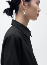 Camisa negra de manga corta confeccionada en mezcla de algodón y lino, con cierre de botones y cuello camisero. Diseño recto y corte holgado.