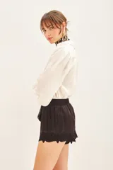 Short negro de satén viscosa con cintura elastizada y detalle de bordado calado en el ruedo.