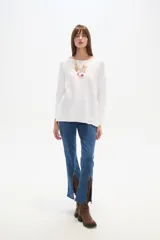 Sweater blanco liso, de corte holgado, con cuello a la base y broches decorativos en los laterales.