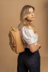 Mochila color marrón de símil cuero con un compartimento principal amplio, bolsillo al frente con cierre, correas ajustables y asa.