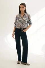 Camisa celeste con estampado abstracto en tonos marrones y azules, de corte clásico, cuello camisero y mangas largas con puños abotonados.