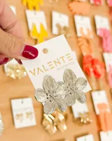 Par de aros colgantes plateados con forma de flor de cinco pétalos, con textura estriada y centro con relieve.