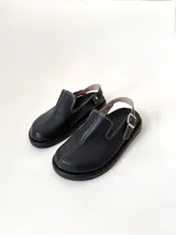 Zuecos color beige de cuero gamuzado, con punta cerrada, suela de goma negra y tira trasera con hebilla metálica.