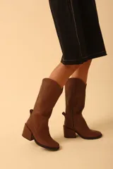 Botas de cuero color marrón con caña media, taco cuadrado y cierre lateral. Diseño de estilo western con puntera fina y detalle de costuras en la caña.