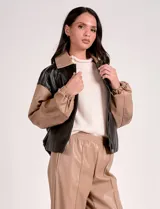 Campera bomber de cuero sintético negra con mangas color beige, cuello clásico y cierre frontal con cremallera.