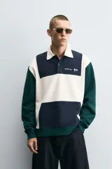 Polo de manga larga con corte relaxed fit, confeccionado en tejido con algodón. Presenta un diseño color block en azul marino, blanco y verde, con cuello solapa con cierre frontal de botonadura. Cuenta con bordados y parches combinados a contraste en delantero y espalda, y acabados en rib.