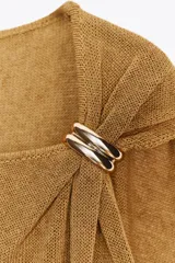 Top dorado de tejido de punto con cuello barco, sin mangas y detalle de fornitura metálica en el hombro.