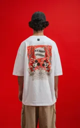 Remera blanca de algodón premium con cuello redondo y calce oversize. Presenta un pequeño estampado en el pecho izquierdo de Mickey Mouse en una pose dinámica sobre un fondo naranja.
