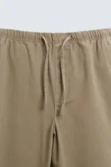 Pantalón verde militar de corte carrot fit, confeccionado en tejido de algodón. Cuenta con cintura elástica ajustable con cordón, bolsillos frontales y un bolsillo trasero de plastrón.