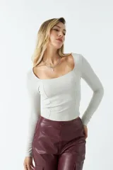 Top negro de punto canalé, de manga larga y escote cuadrado.