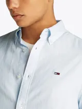 Camisa celeste de manga larga, confeccionada en algodón y lino, con cuello abotonado, cierre con botones, corte regular y logo de Tommy Jeans bordado en el pecho.