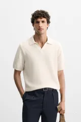 Polo color crema de punto con cuello solapa y abertura frontal en V.