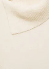 Sweater color beige de tejido de punto, con cuello solapa alto y mangas largas.