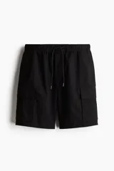 Short cargo negro de tejido grueso de algodón con cierre decorativo y cintura elástica con cordón para ajustar. Tiene bolsillos al bies y bolsillos de solapa con cierre autoadherente en las piernas y atrás. Corte estándar para una silueta clásica y cómoda.