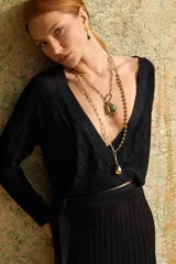 Cardigan crop negro con escote en V cruzado y ajuste en la cintura. Tejido en punto desagujado con lurex.