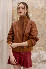 Chaqueta de cuero color marrón con cuello alto y puños de algodón. Cierre delantero con cremallera y dos bolsillos laterales. Talle único.