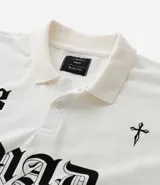 Remera boxy de mangas cortas confeccionada en algodón negro, con cuello polo y estampado frontal con el número 93, la palabra MAD en estilo gótico y una cruz. El algodón es certificado BCI.