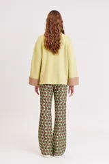 Pantalón acampanado con estampado geométrico en tonos marrón, verde oliva y verde claro.