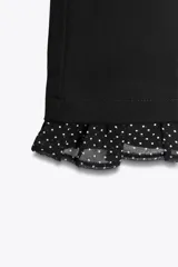 Pantalón negro de tiro alto con corte mini flare y volantes con estampado de lunares en el bajo.