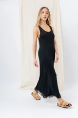 Vestido midi color beige, de tejido tipo seda, con escote redondo, sin mangas y detalle de flecos en el ruedo.