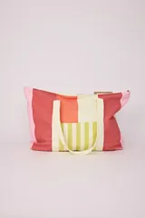 Bolso tote playero con diseño de bloques de color rosa, rojo, naranja, blanco y verde a rayas. Tiene asas de color crema.