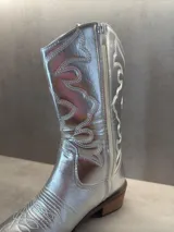 Botas texanas plateadas con bordados decorativos y taco bajo.
