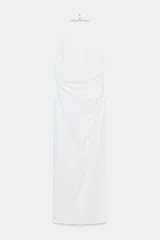 Vestido midi blanco con cuello halter, escote pico, detalle de frunces en el delantero y abertura. Cierre en espalda con cremallera oculta y botones.