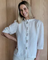 Camisa color beige claro con cuello con volados y mangas 3/4 abullonadas.