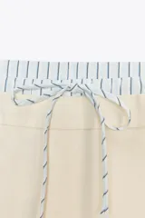 Pantalón de tiro alto color crema, con cintura combinada a contraste tipo boxer con cordones ajustables. Detalle de pinzas en delantero, bolsillos laterales y falso bolsillo de vivo en espalda.