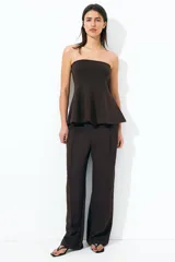 Pantalón de vestir marrón de punto con pinzas, tiro alto con cintura elástica, bolsillos al bies y piernas amplias con raya adelante.
