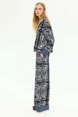 Pantalón de lino liviano con estampado paisley en tonos azul y blanco. Modelo de corte holgado con cintura elástica de tiro alto, bolsillos laterales discretos y piernas amplias.