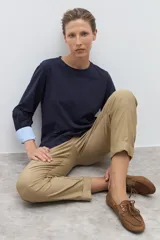 Remera de manga larga color azul marino con cuello redondo. Los puños de las mangas son doblados y revelan un forro de tela a rayas finas blancas y celestes.