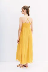 Vestido largo amarillo de gasa con breteles regulables que se cruzan en la espalda y bordado de mostacillas a tono.