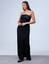 Vestido de fiesta corto strapless, color negro, confeccionado en crepe. Presenta escote recto con aplique de moño en satén y tajo en la parte delantera.
