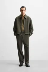 Pantalón largo color verde oscuro, de corte recto y tiro medio. Confeccionado en tejido con viscosa, con cintura elástica, bolsillos laterales y trasero de vivo. Cierre frontal con cremallera y botón.