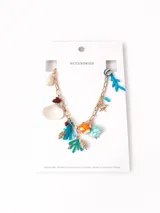 Collar dorado con cadena de eslabones y dijes colgantes con motivos marinos: conchas, corales, peces y cuentas de colores.