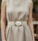 Cinturón de cuero color beige con hebilla ovalada en tono bronce, con centro de nácar.