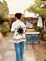 Cardigan tejido artesanalmente en lana color crudo, con diseño de copo de nieve en la espalda y bordados a mano.