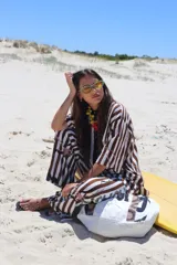 Camisa de manga corta, con cuello y botones frontales, de corte holgado. Presenta un estampado de rayas verticales anchas en tonos marrón y blanco, con salpicaduras o manchas en tonos rosados y negros.