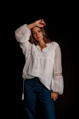 Camisa blanca de plumetí con cuello mao, mangas largas abullonadas con puños elásticos y cordón con borlas en el escote.